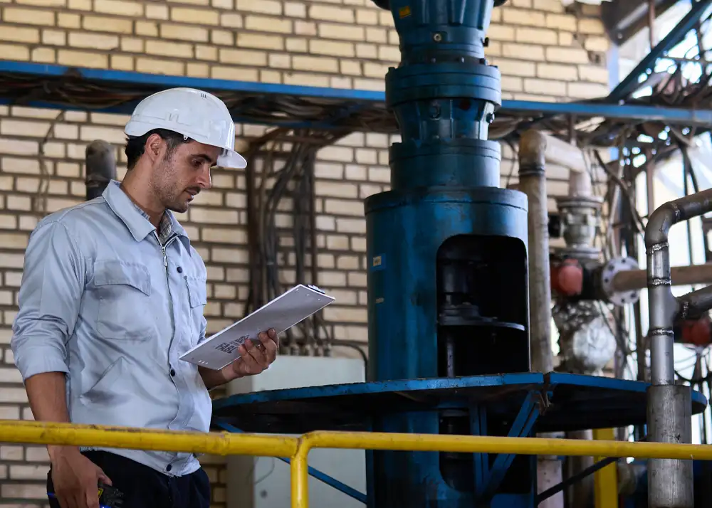 مهندس ناظر در حال بررسی اسناد فنی و نظارت بر تجهیزات خط تولید کارخانه.